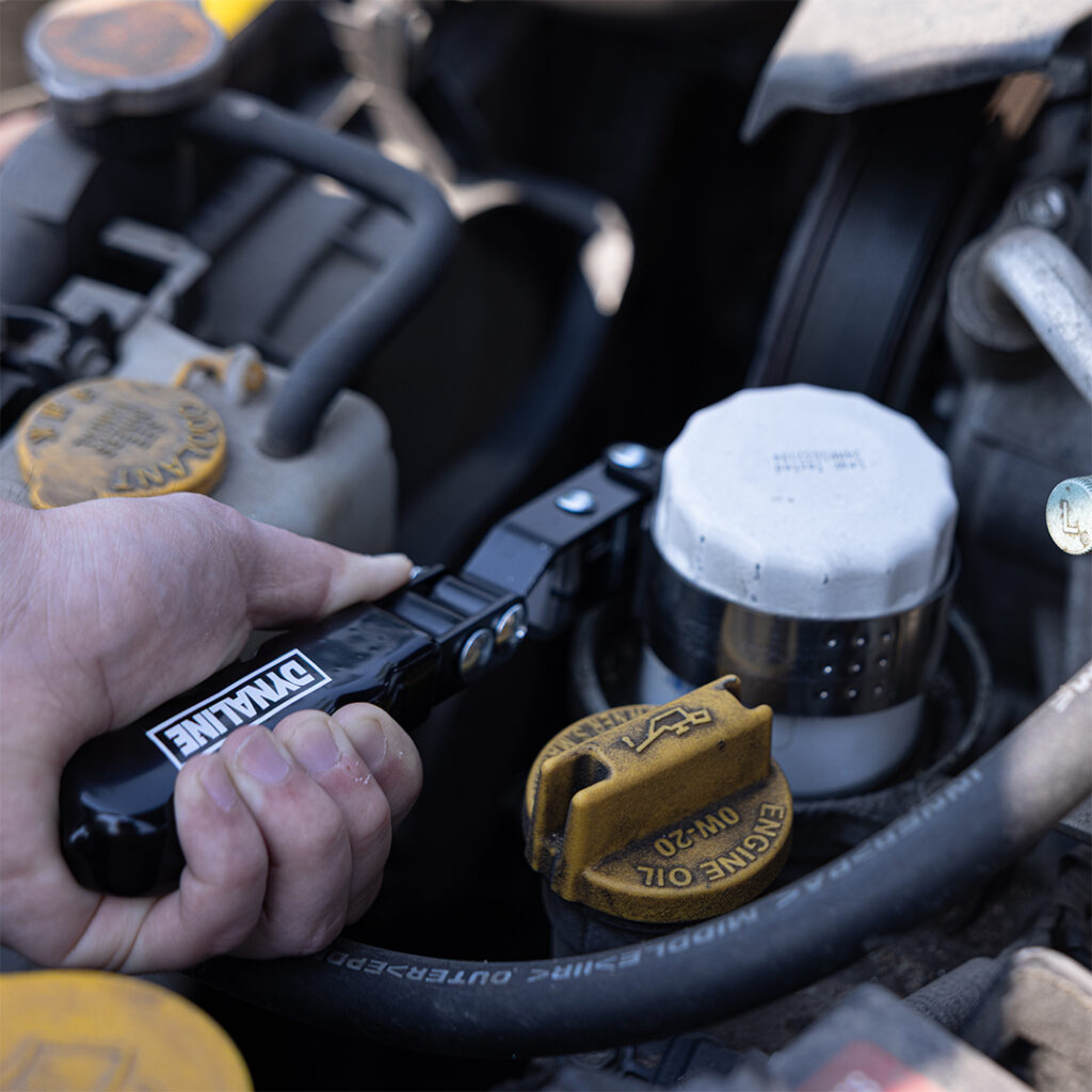Hand checking fluid levels under a vehicle hood with a gauge tool